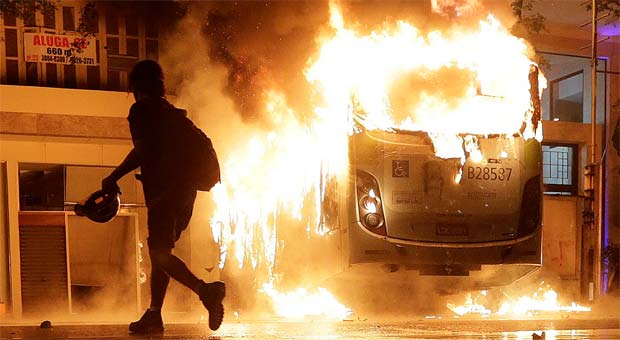 Homem passa por ônibus em chamas durante os protestos de apoio aos professores em Greve (REUTERS/Ricardo Moraes ) Homem passa por ônibus em chamas durante os protestos de apoio aos professores em Greve (REUTERS/Ricardo Moraes )