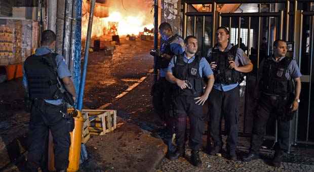 Policiais foram cercados durante o protesto desta terça-feira, prédio da UPP foi danificado pelos manifestantes (CHRISTOPHE SIMON / AFP) Policiais foram cercados durante o protesto desta terça-feira, prédio da UPP foi danificado pelos manifestantes (CHRISTOPHE SIMON / AFP)
