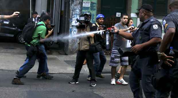 Policial joga spray de pimenta em pessoas na rua no dia da abertura da Copa. Imprensa vê abusos (Pilar Olivares/Reuters) Policial joga spray de pimenta em pessoas na rua no dia da abertura da Copa. Imprensa vê abusos (Pilar Olivares/Reuters)