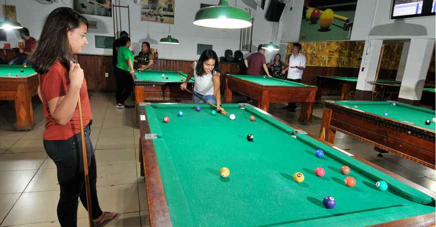 Mão do homem jogando sinuca no bar com bola de snooker